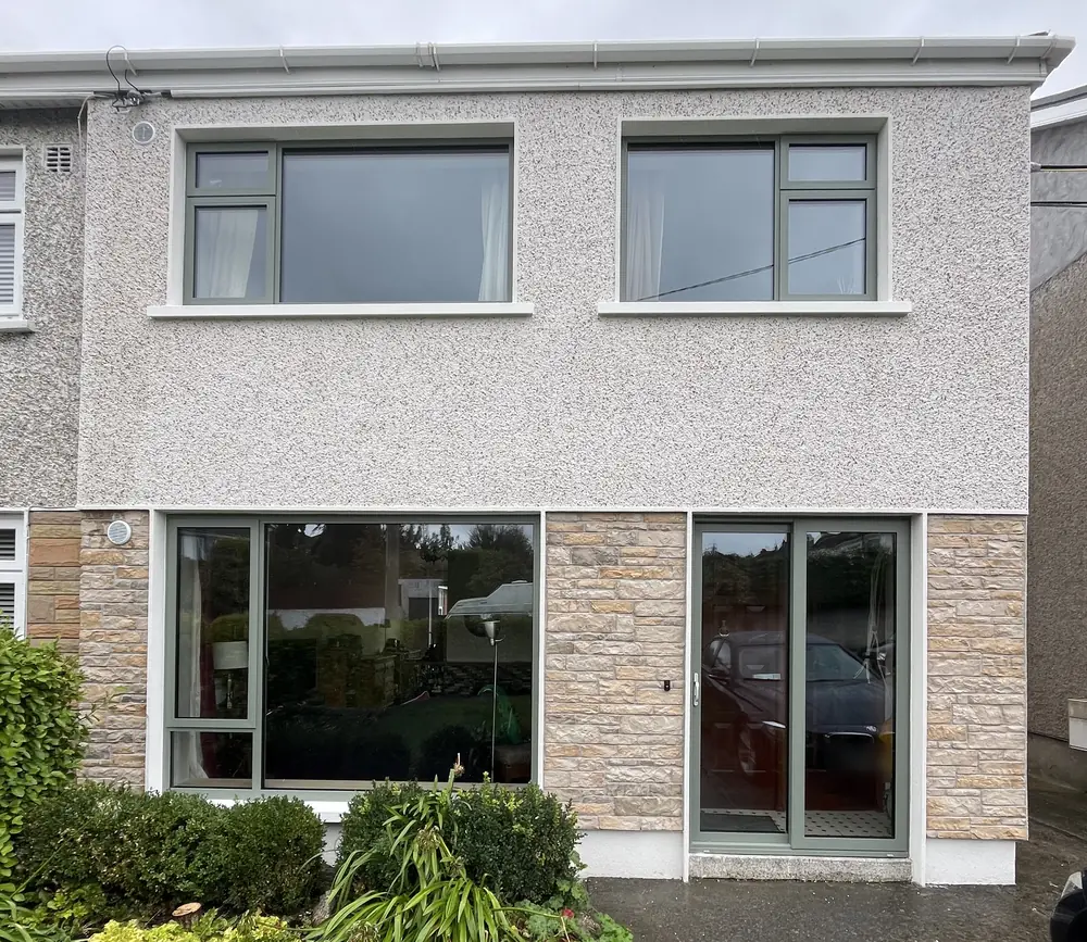 A semi-detached house after external wall insulation, with a speckled render upstairs and a stone-effect finish downstairs.