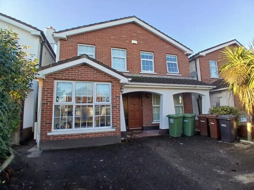A finished detached house with a red brick front and a white rendered porch.